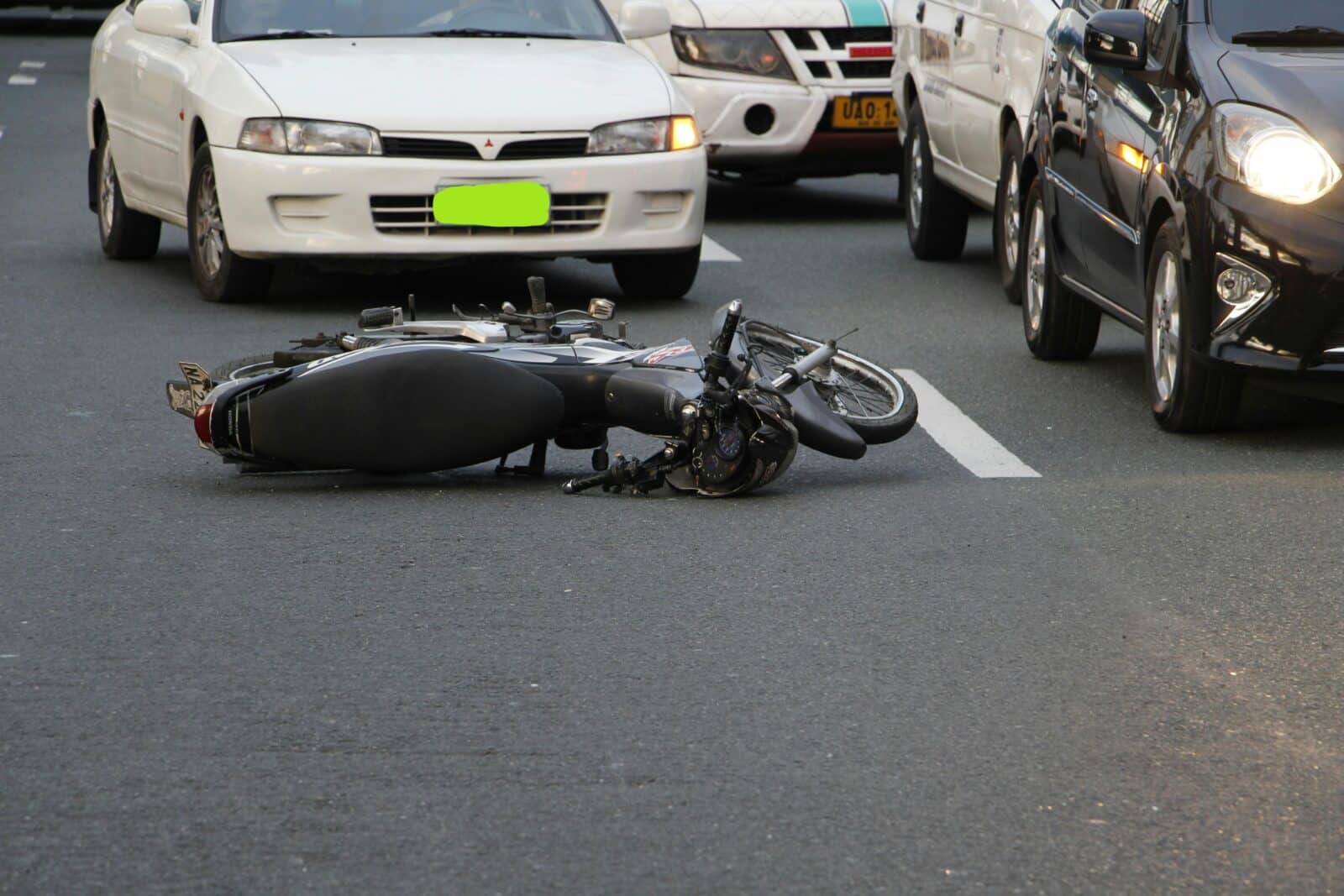 A crashed motorcycle lies in the middle of a city street.