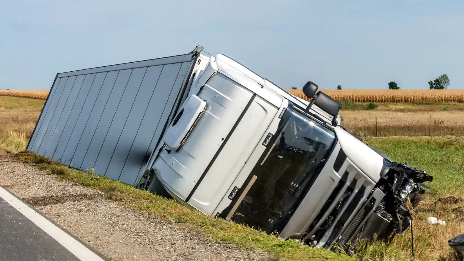 Overturned truck lying on its side beside the roadway after a crash