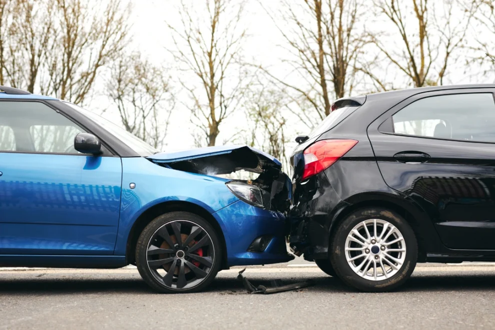 Two damaged cars after a collision, with visible dents and scratches on their exteriors.